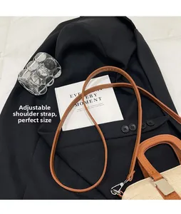 Detail view of the brown leather shoulder bag with an adjustable strap on a dark jacket