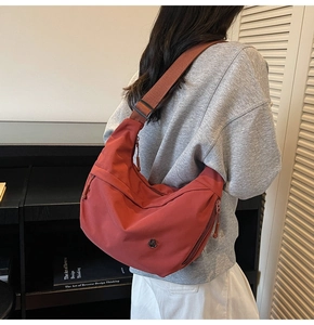 Détail du sac bandoulière en nylon bordeaux avec sangle réglable et poche latérale zippée discrète