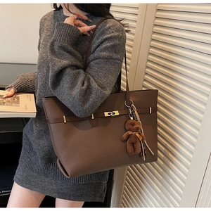 Detail of dark brown pebble leather tote bag with metal twist lock and cute bear charm