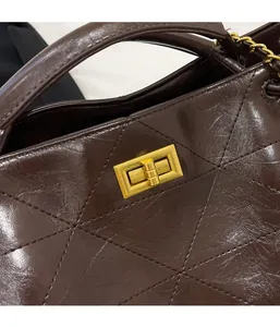 Detail of dark brown quilted leather bag featuring a gold rectangular twist lock closure