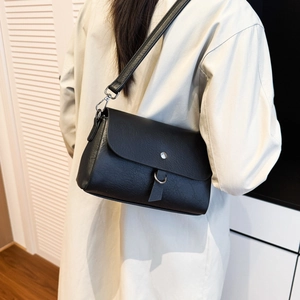 Detail of minimalist black leather crossbody bag with silver buckle worn by a model