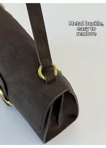 Detalle de bolso tote de cuero marrón oscuro con hebilla metálica dorada extraíble lateral