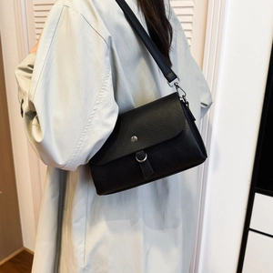 Close-up of black crossbody bag with silver magnetic clasp and lychee leather texture