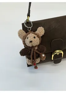 Primer plano de un oso de peluche marrón con bolso de perlas en un bolso de cuero retro