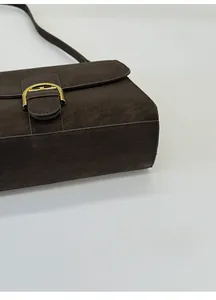 Detalle del bolso retro marrón oscuro con base reforzada y cierre metálico dorado