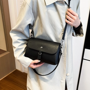 Close-up of black crossbody bag with lychee grain texture and silver metal buckle