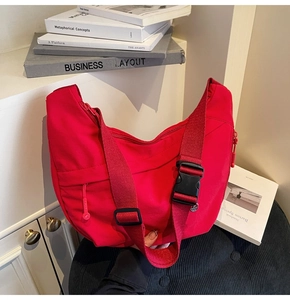 Détail du sac bandoulière en nylon rouge avec boucle noire et fermeture éclair cachée