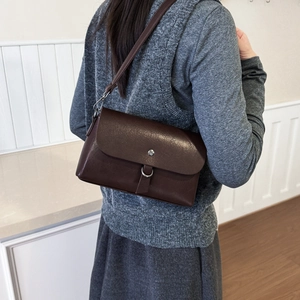 Brown vintage flap bag with silver hardware worn over a grey knit outfit by model