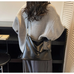Dettaglio di una borsa a spalla nera con hardware dorato e mini pochette coordinata