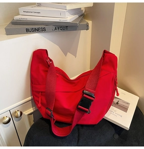 Détail du sac bandoulière croissant en nylon rouge avec sangle réglable et poches zippées
