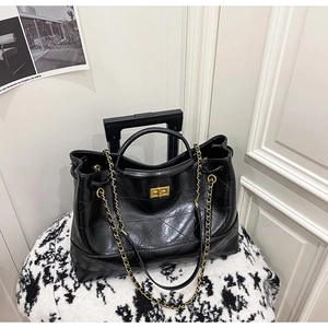 Détail du sac cabas en cuir matelassé noir avec chaînes dorées et fermoir rotatif en métal