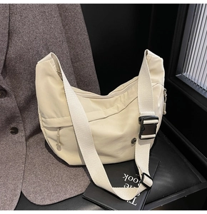 Détail du sac croissant en nylon beige avec bandoulière large et boucle noire