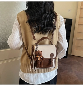 Detalle de bolso tote vintage bicolor beige y marrón con amuleto de oso de peluche