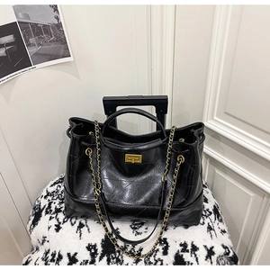 Détails du sac cabas matelassé noir avec finitions en cuir huilé et chaînes dorées