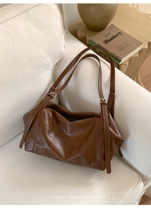 Detail of dark brown waxed leather tote with dual silver buckle adjustable straps