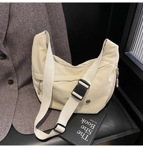 Détail du sac bandoulière en nylon crème avec large sangle sur cuir noir