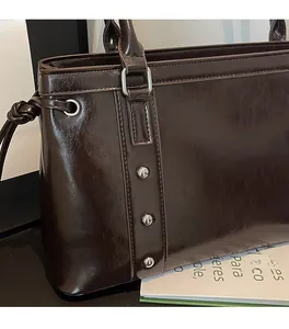 Detail of dark brown oil wax leather shoulder bag with silver rivets and knotted strap