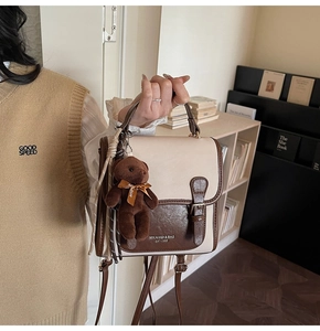 Detail of vintage beige backpack with brown trim and cute bear keychain charm