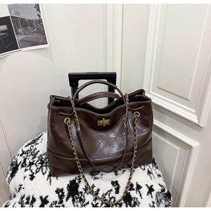 Détail du sac fourre-tout matelassé marron foncé avec fermoir doré et bandoulière