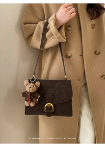 Detail of retro dark brown square bag with gold buckle and teddy bear charm