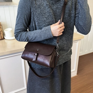 Detailed view of deep brown flap bag with metal buckle and adjustable shoulder strap