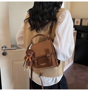 Detail of vintage brown patchwork backpack featuring a cute teddy bear charm and metal buckles
