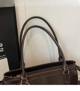 Close-up of brown tote bag showing glossy leather texture and metal zipper detail