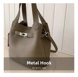Close-up of elephant gray lychee leather bucket bag with silver metal lock and hooks