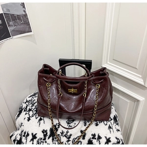 Détail de sac cabas en cuir matelassé bordeaux avec fermoir pivotant en métal doré