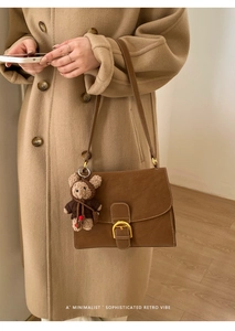 Retro brown suede shoulder bag detail with plush bear charm and gold D-ring buckle