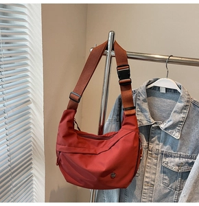 Détail du sac bandoulière en nylon rouge en forme de croissant avec sangle réglable et boucle