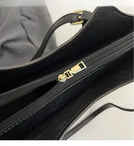 Detail of smooth gold zipper and black textured leather strap on a large tote bag
