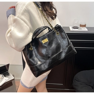 Détail du sac cabas matelassé noir avec bandoulière chaîne dorée et fermoir pivotant en métal