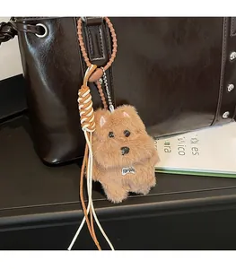 Detail of plush dog keychain with metal bone tag and woven cord on a leather tote