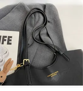 Close-up of black lychee grain leather tote bag with gold hardware and rabbit pendant
