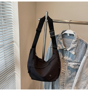 Détail du sac croissant en nylon noir avec boucle tactique et logo argenté sur cintre