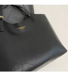 Detailed close-up of black PU leather tote bag with gold stamped fashion logo and strap