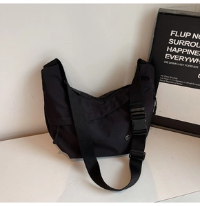 Détail d'un sac besace en nylon noir avec bandoulière large et boucle en plastique robuste