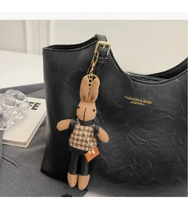 Detailed view of a brown knit bunny charm on a black textured tote bag accessory