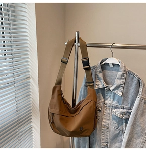 Détail du sac croissant en nylon marron avec bandoulière réglable sur un cintre en métal