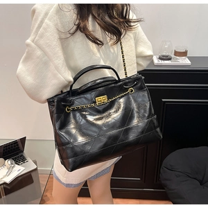 Detailed view of black quilted tote bag with gold chain and polished leather texture