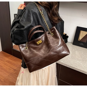 Détail d'un grand sac cabas matelassé marron avec fermoir doré et bandoulière en chaîne