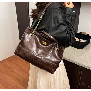 Détail du sac cabas en cuir matelassé marron foncé avec chaîne dorée et fermoir tournant