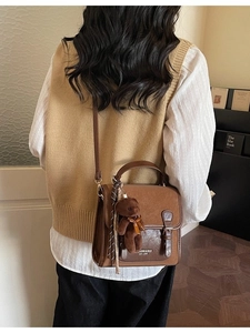 Retro brown PU leather crossbody bag with flap and plush bear charm worn by a model