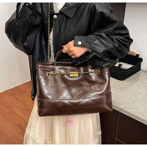 Detail of vintage brown quilted tote bag with golden twist lock and chain strap