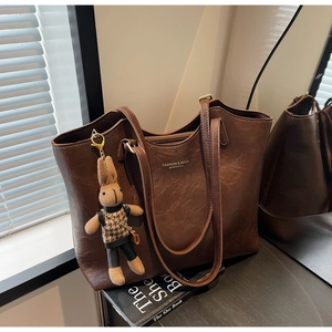 Detail of vintage brown leather tote bag with woven rabbit pendant and fashion logo