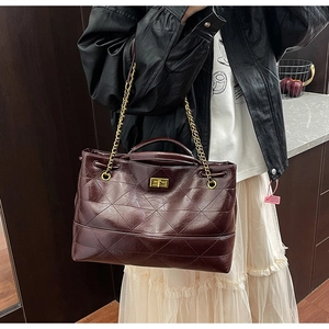 Détail du sac cabas bordeaux montrant la texture matelassée et le fermoir doré rotatif