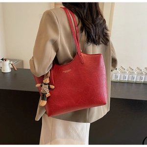 Red large-capacity tote bag with rabbit charm shown worn on a model's shoulder