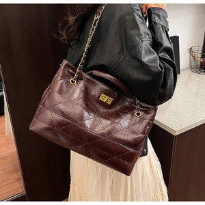 Close-up of wine red quilted tote bag with golden twist lock and chain strap