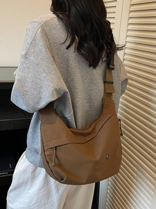 Sac bandoulière demi-lune en nylon marron à sangle réglable porté par un mannequin